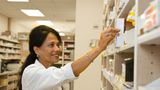 Woman pharmacist puts medicine on shelf