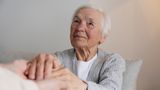 Older woman holding hands with carer