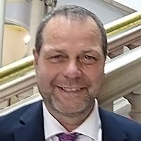 Paul Kingis smiling for his headshot photo in front of the county hall steps
